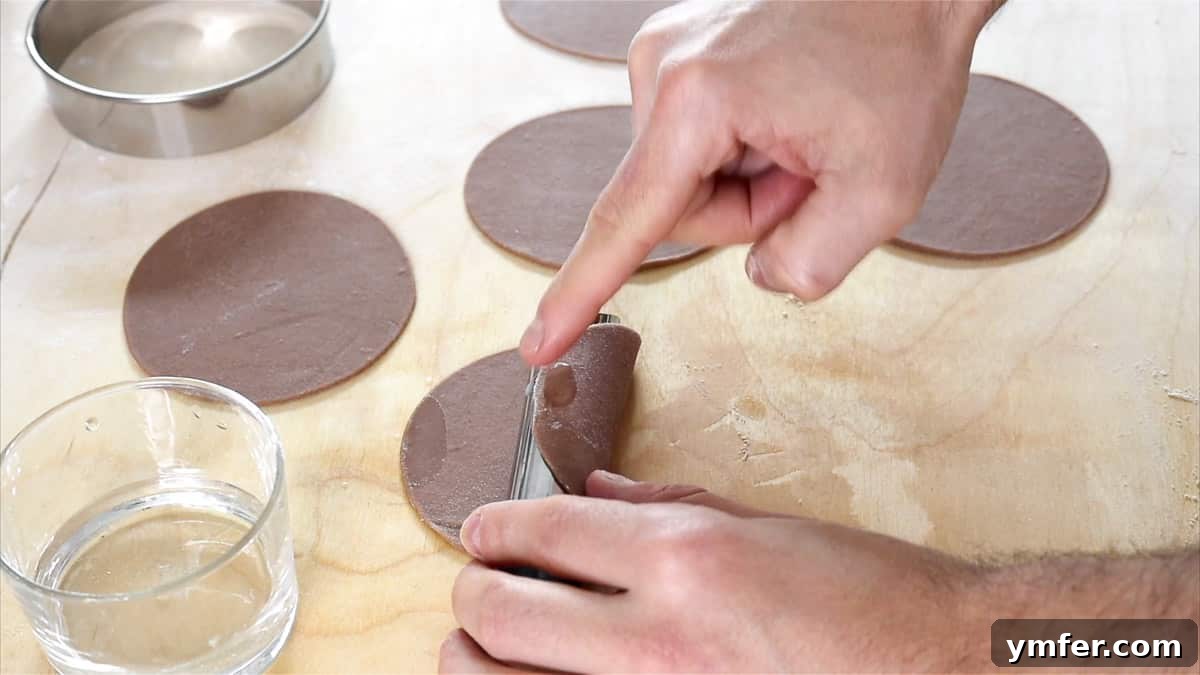 Sealing the edges of the cannoli dough around the metal tubes.