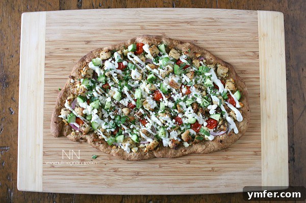 Greek Chicken Souvlaki Pizza 4 Chicken Souvlaki Pizza on a cutting board drizzled with tzatziki sauce and fresh herbs.
