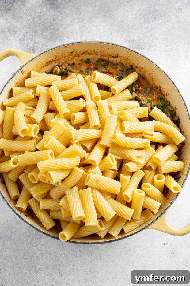 Adding pasta to a dish of creamy tomato sauce. 