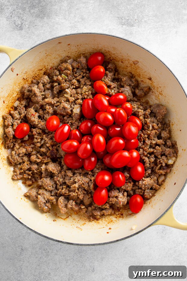 Tomatoes in a skillet with Italian sausage. 