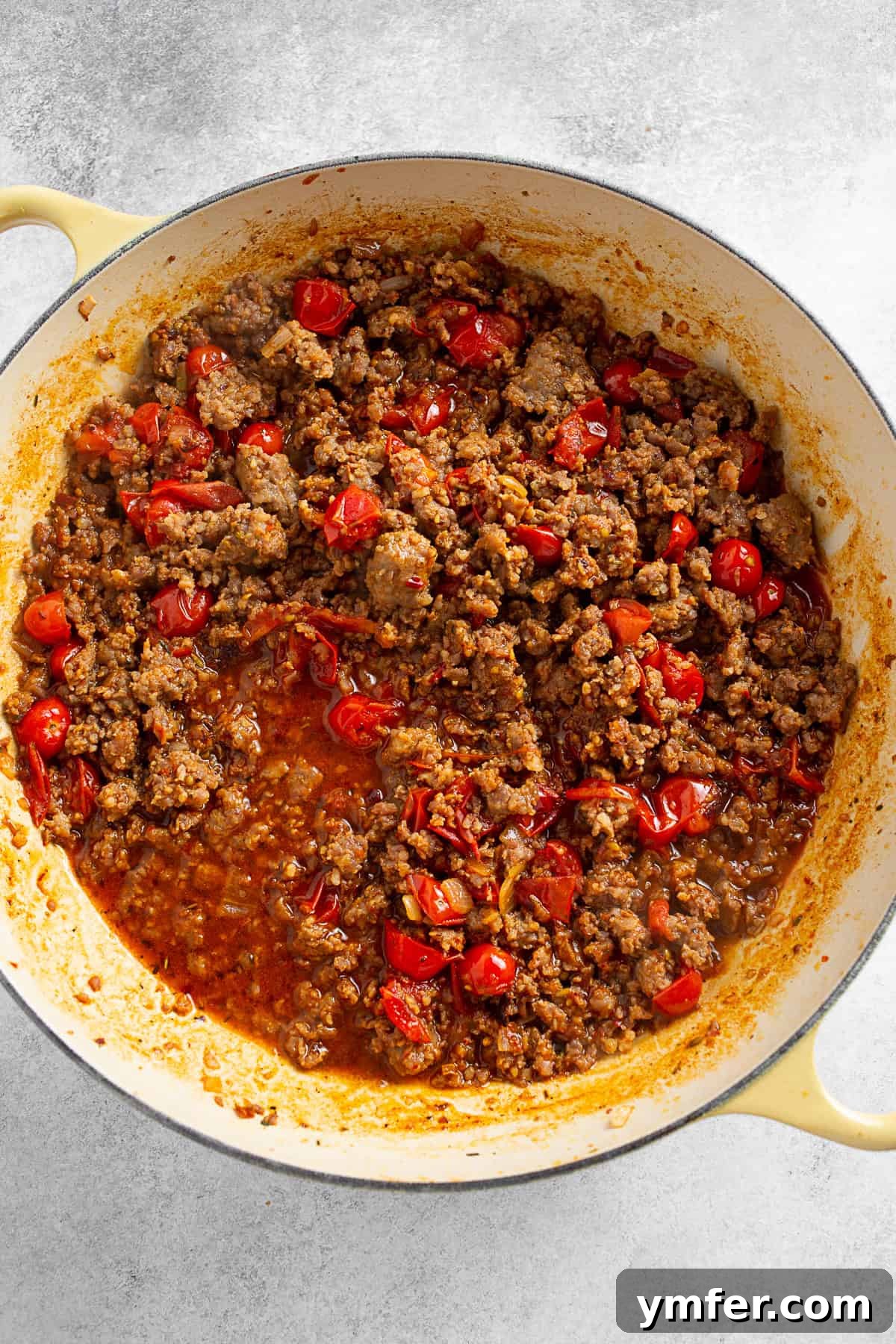 Italian sausage and tomatoes in a skillet. 