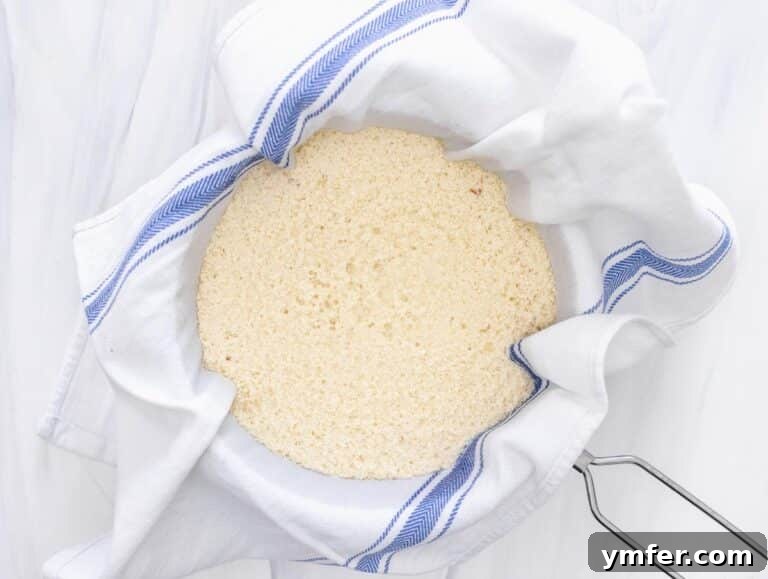 Creamy Vegan Ricotta 29 Curdled soy milk being poured into a strainer lined with a cloth, separating the curds from the whey.