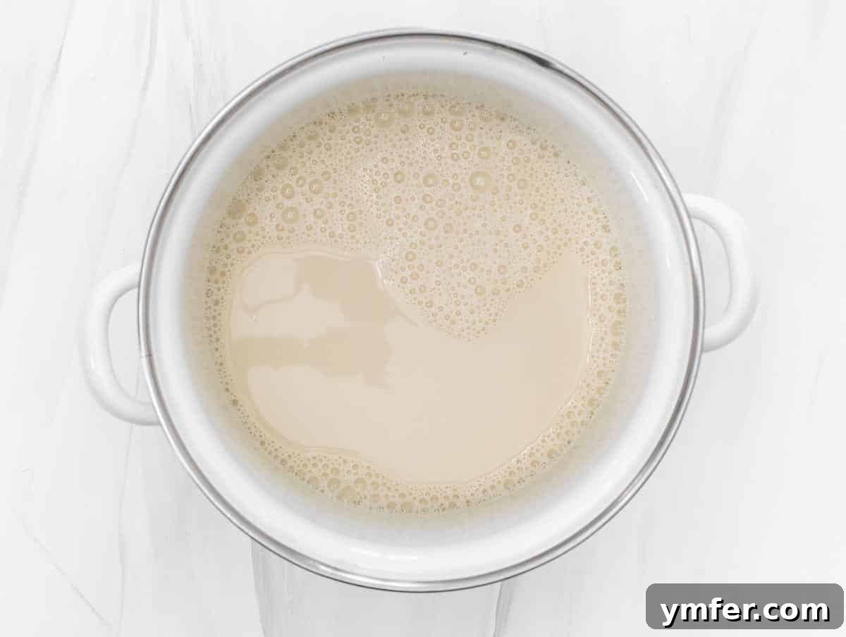 Creamy Vegan Ricotta 7 Soy milk heating in a stainless steel pot on a stovetop, showing the initial stage of ricotta preparation.