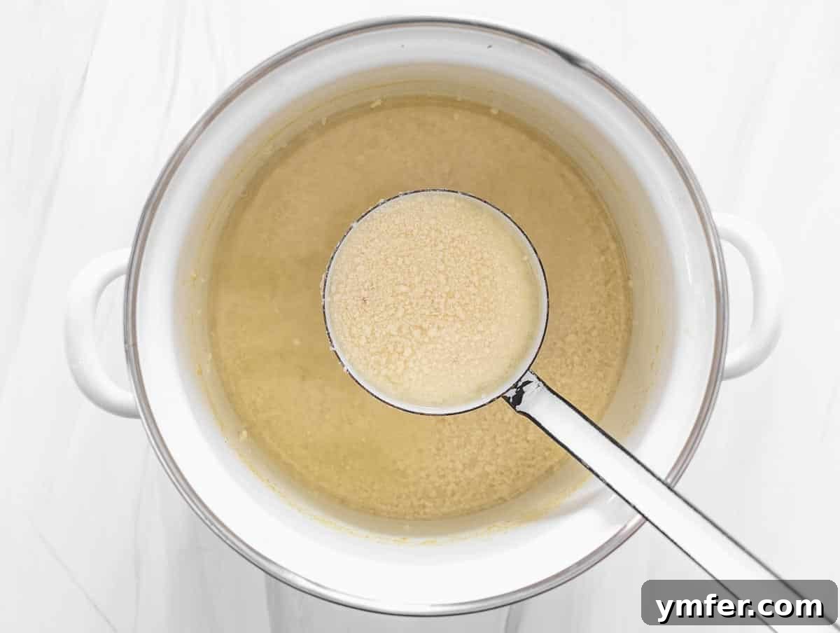 Creamy Vegan Ricotta 8 Soy milk actively curdling in a pot after vinegar has been added, displaying the separation of curds and whey.