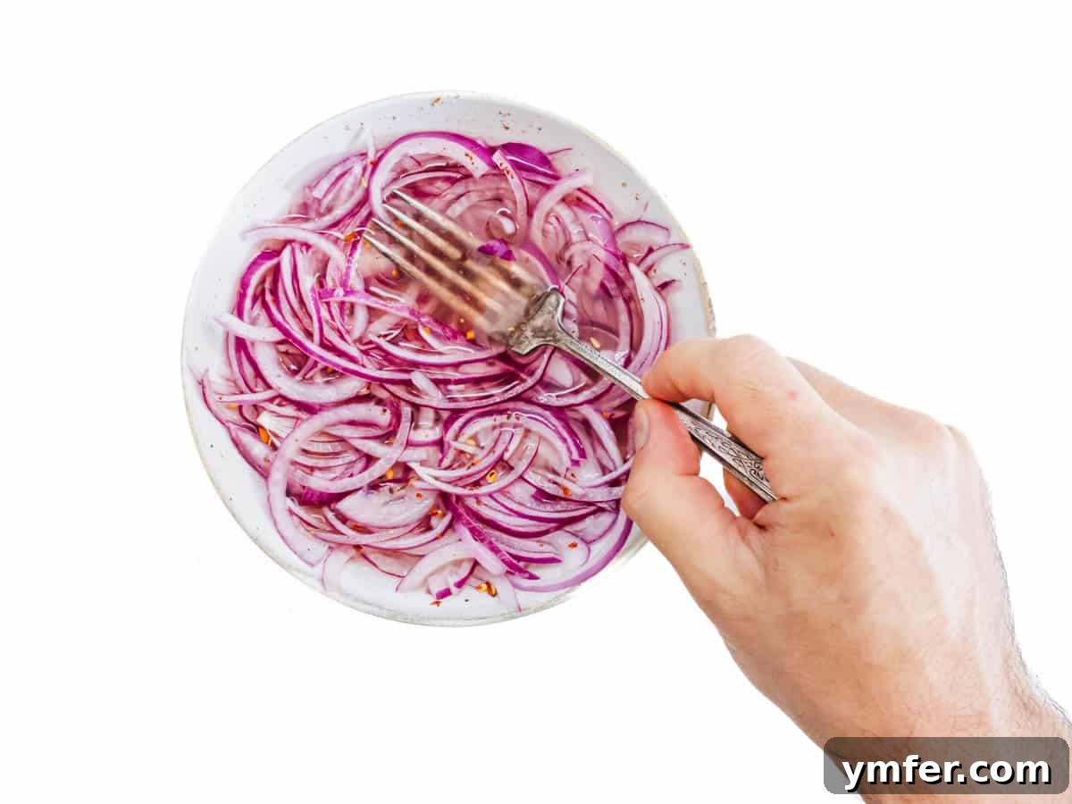 Red onions in vinegar and a hand