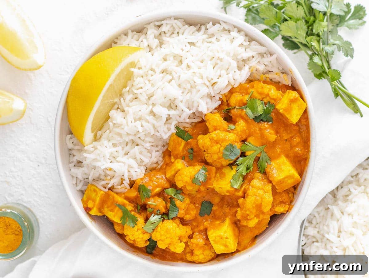 Nourishing Plant Power Meals 33 Creamy tofu curry served on basmati rice in a bowl, garnished with a lemon wedge and cilantro