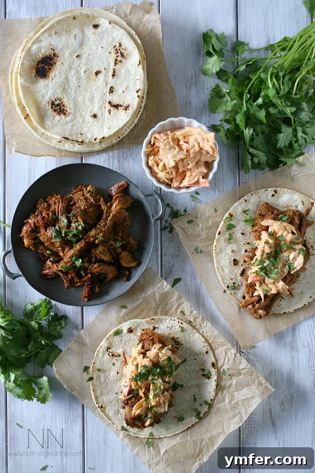 These slow cooker ginger beer pulled pork tacos are topped with a spicy chipotle cole slaw and served on toasted corn tortillas. Ginger Beer Pulled Pork Tacos on a table, served with spicy chipotle coleslaw on toasted corn tortillas.