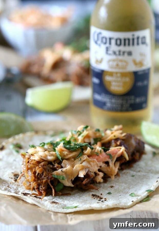 Zesty Ginger Beer Pulled Pork Tacos 2 Close-up of Ginger Beer Pulled Pork Tacos on a plate, generously topped with slaw.