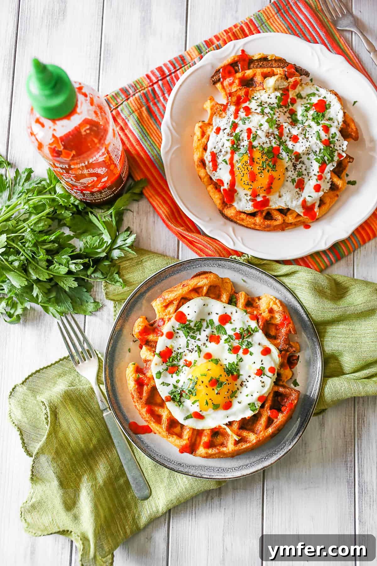 Perfectly portioned Cheddar Sausage Cornmeal Waffles, a hearty and flavorful start to your day. Two plates of Cheddar Sausage Cornmeal Waffles, ready to be enjoyed.