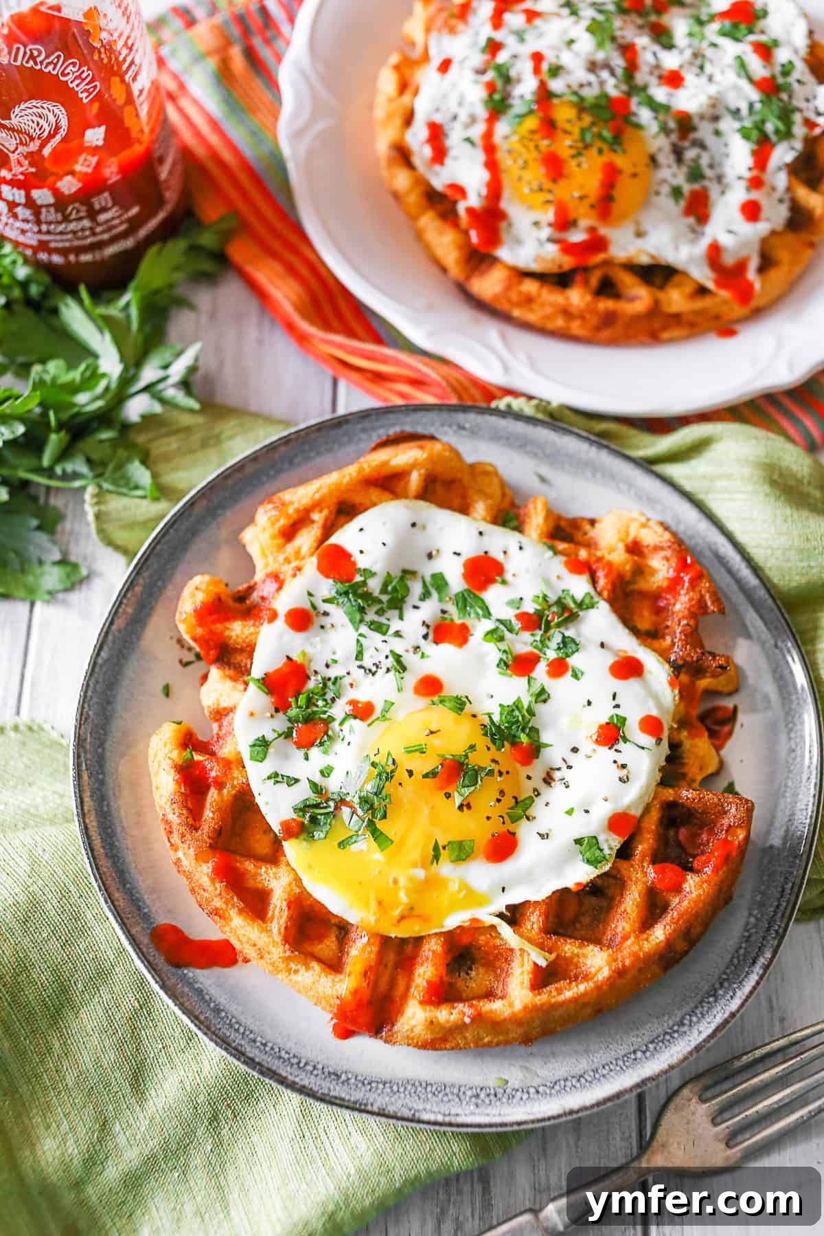 Cheesy Sausage Cornmeal Waffles 2 A plate of Cheddar Sausage Cornmeal Waffles drizzled generously with sriracha.