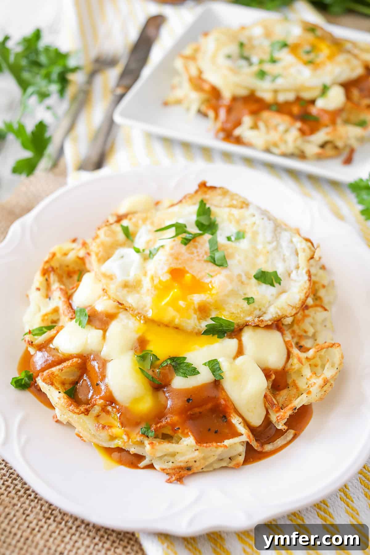 Waffled Hash Brown Poutine 2 A single plate of Poutine Hash Brown Waffles, crowned with a fried egg, ready to be enjoyed as a savory breakfast.