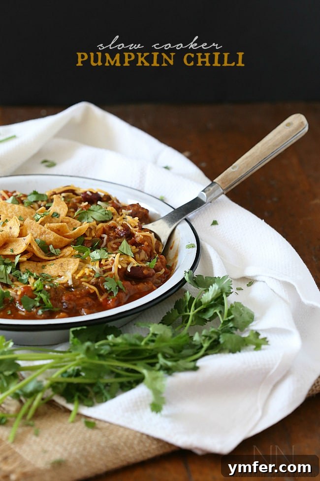 Hearty Slow Cooker Pumpkin Chili with Spicy Italian Sausage A steaming bowl of Slow Cooker Pumpkin Chili, packed with pumpkin puree, spicy Italian sausage, and various beans and vegetables, perfect for cold weather.