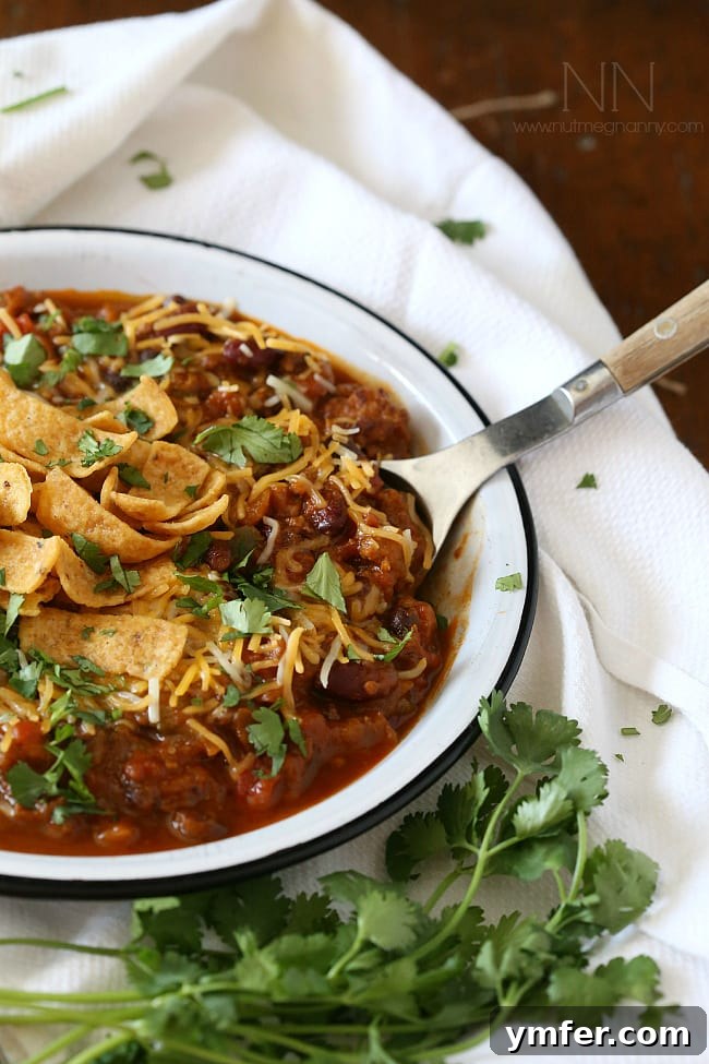 Best Slow Cooker Pumpkin Chili Recipe for Fall A spoon scooping a generous portion of Slow Cooker Pumpkin Chili, highlighting the vibrant ingredients and inviting warmth.
