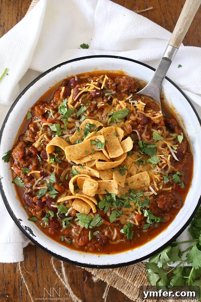 Easy Slow Cooker Pumpkin Chili for Dinner Top-down view of Slow Cooker Pumpkin Chili garnished with fresh cilantro and shredded cheese, ready to be served.