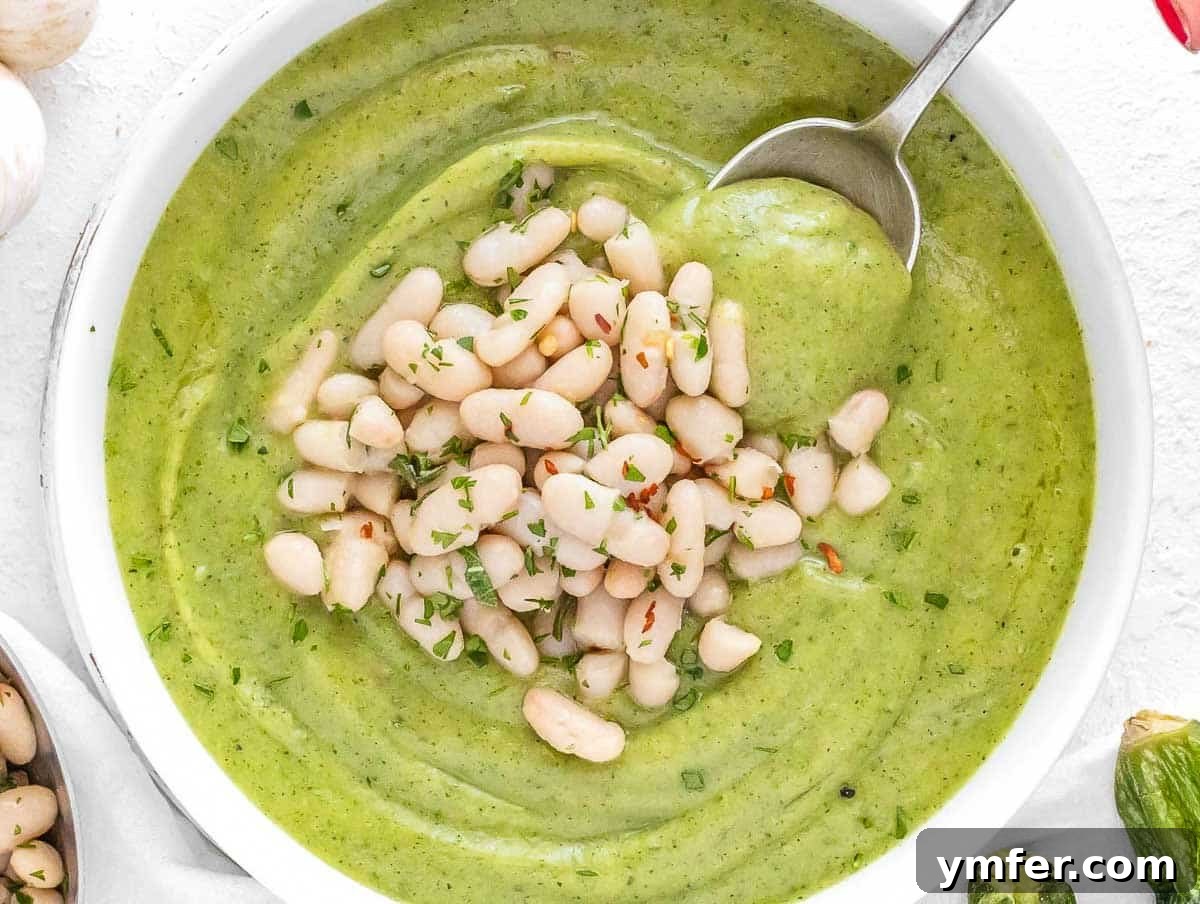 Streamline Your Week with Vegetarian Meal Prep 4 Fresh zucchini soup served with beans and a spoon, ideal for light and healthy meal prep.