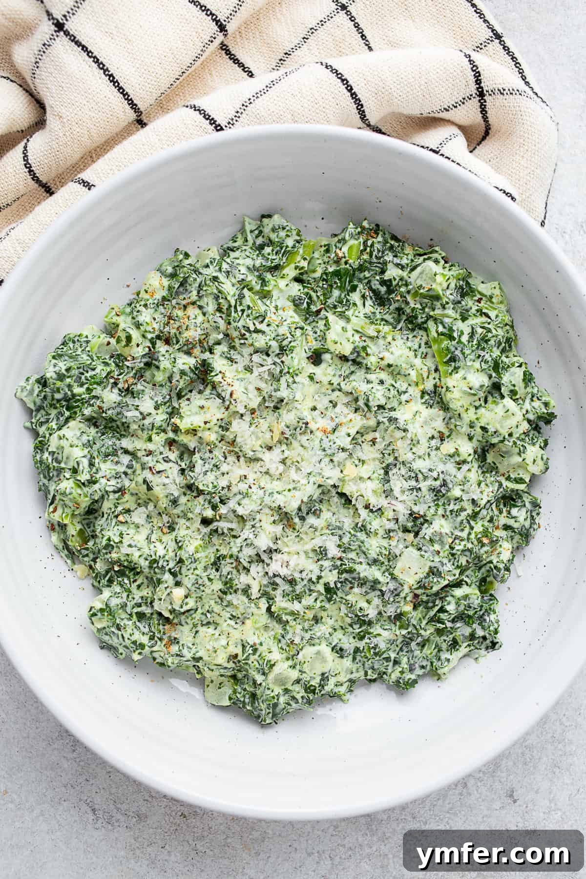 Velvety Creamed Kale 2 Creamed Kale in a bowl with a napkin on a table.