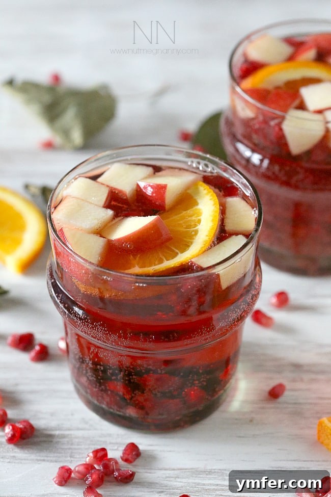 Easy Make-Ahead Holiday Sangria A large pitcher of Thanksgiving sangria filled with fruit and red wine, ready to be served, highlighting its appealing presentation.