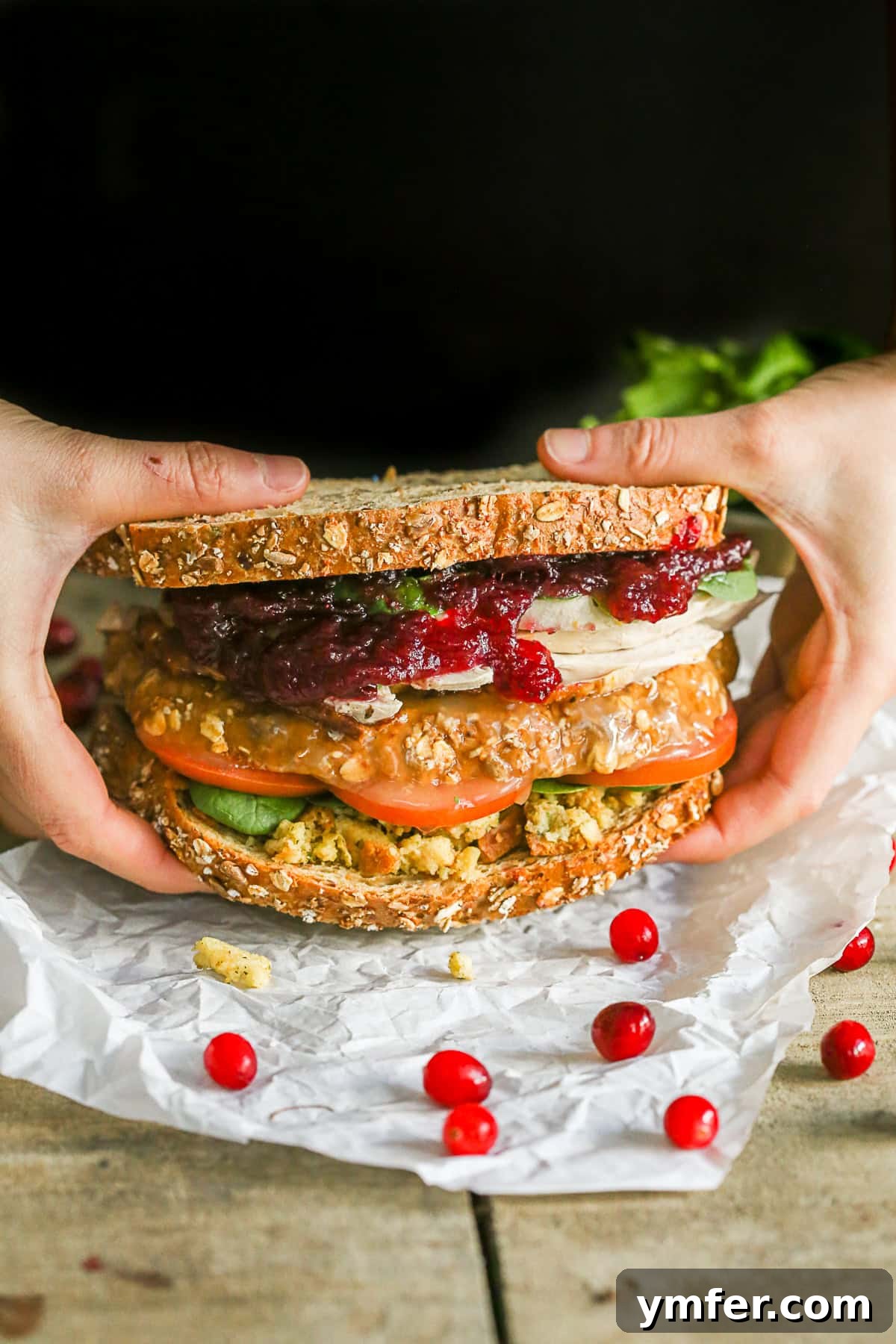 This leftover Thanksgiving sandwich with moist maker is the perfect way to pay homage to your favorite Friends episode. All the taste of a Thanksgiving dinner with a secret gravy soaked moist maker middle! Two hands gently lifting a fully assembled Leftover Thanksgiving Sandwich, revealing its bountiful layers of holiday goodness.