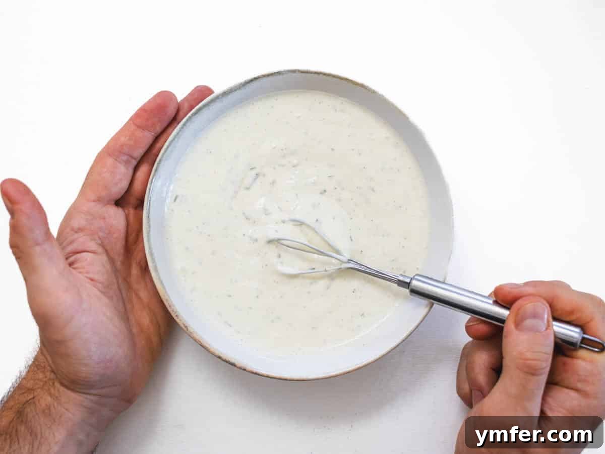 Creamy Vegan Ranch 8 Hands whisking the vegan ranch dressing in a bowl, showing the creamy texture developing.