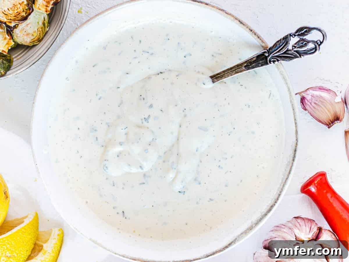 Creamy Vegan Ranch 9 A close-up of creamy vegan ranch dressing with a hand holding a spoon, ready to taste.