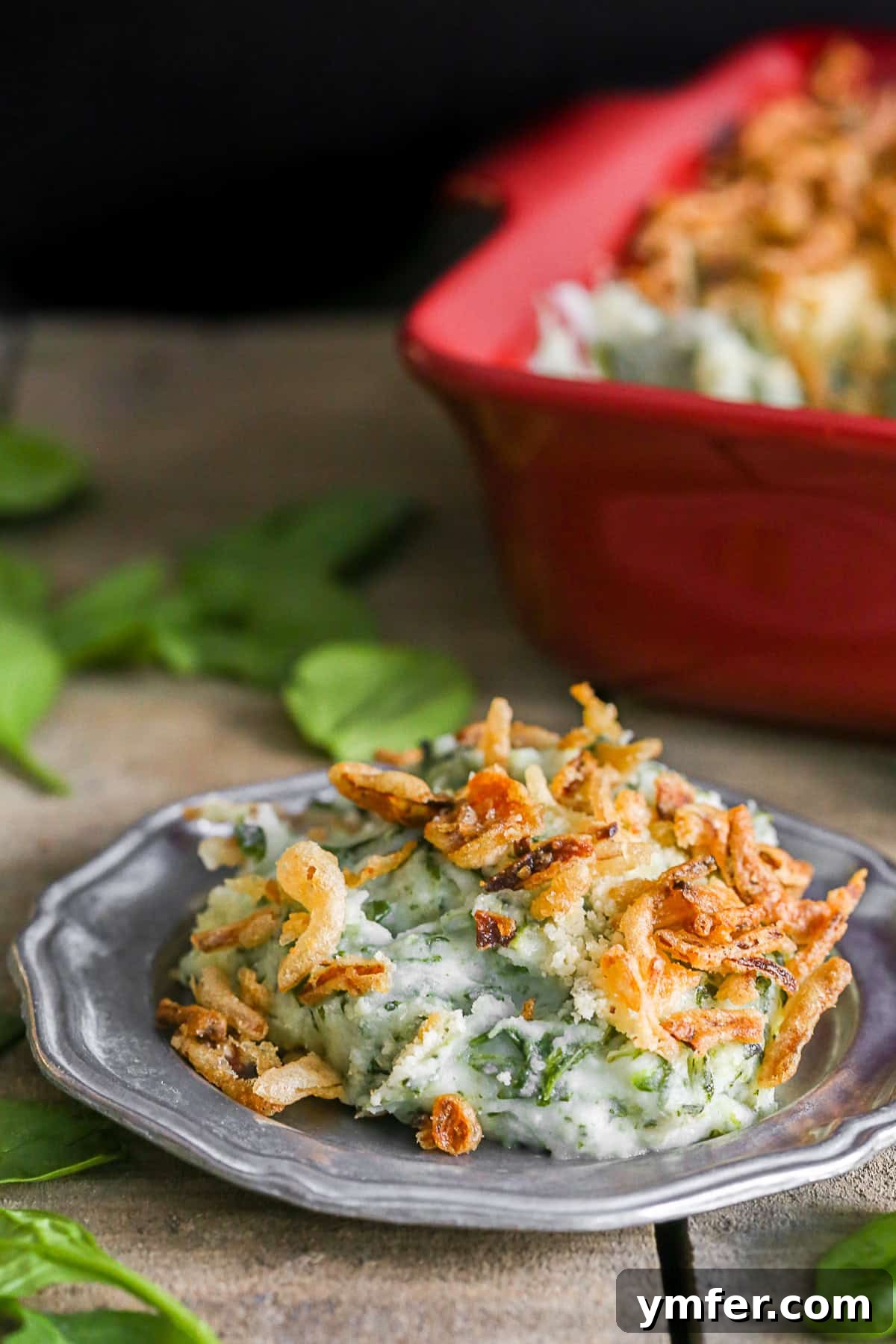 Golden Spinach Parmesan Mashed Potato Bake 2 Creamy Spinach Parmesan Baked Mashed Potatoes served in a rustic dish and scooped on a plate, ready to be enjoyed.