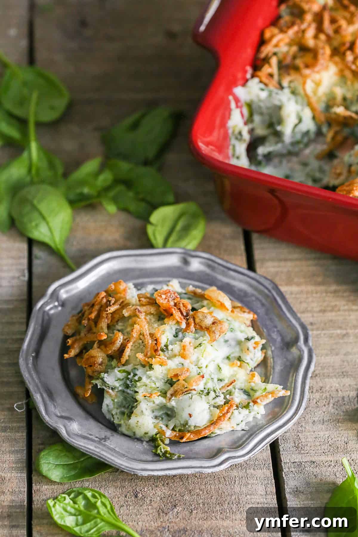 Golden Spinach Parmesan Mashed Potato Bake 3 Close-up of golden-brown Spinach Parmesan Baked Mashed Potatoes in a small metal dish, highlighting the crispy fried onion topping.
