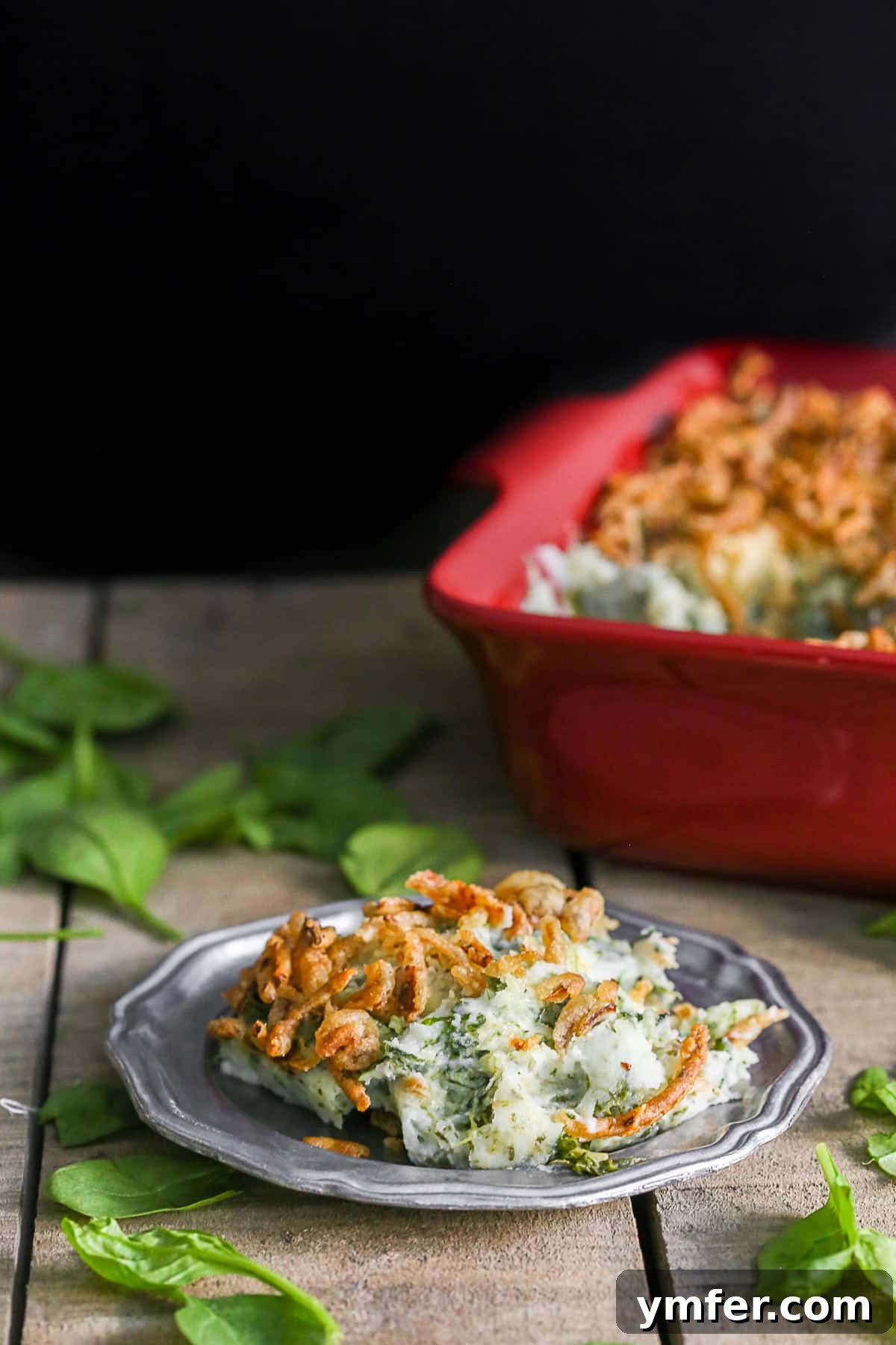 Golden Spinach Parmesan Mashed Potato Bake 5 A scoop of Spinach Parmesan Baked Mashed Potatoes on a white plate, showcasing its creamy texture and golden topping.