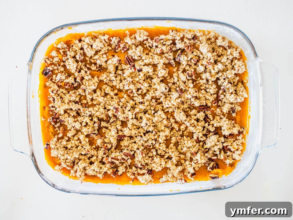 Golden Vegan Sweet Potato Delight 8 A vibrant sweet potato mash covered with a golden oat and pecan streusel topping, ready to be baked in a casserole dish