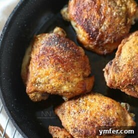 crispy pan roasted chicken thighs in a skillet sprinkled with kosher salt