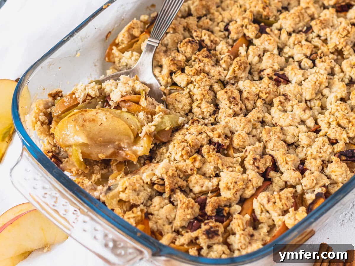 Plant-Based Apple Crumble 13 A serving of vegan apple crisp with a silver spoon, showing the tender apples and crispy topping