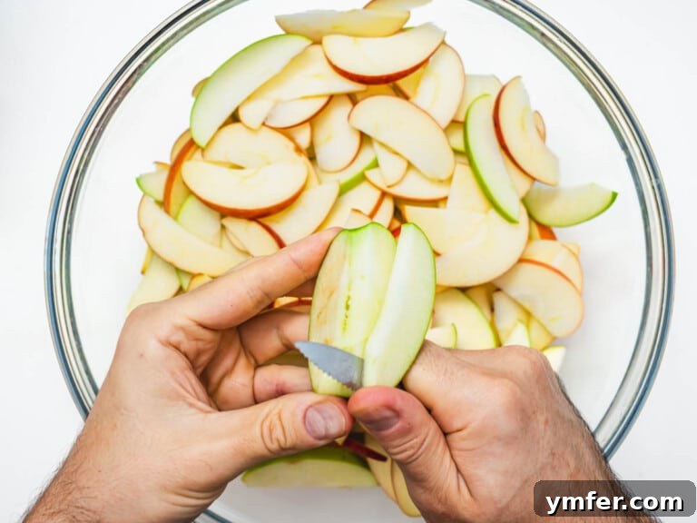 Plant-Based Apple Crumble 17 hands and a knife slicing apple into a casserole