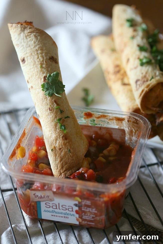 Taquitos with Fresh Salsa Crispy Creamy Chicken Taquitos being dipped into a vibrant red salsa.