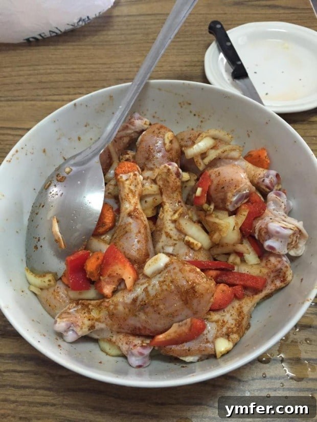 Prep stage for Grenadian Chicken Stew, featuring bone-in chicken and colorful diced vegetables. Uncooked Grenadian Chicken Stew ingredients in a bowl, showing fresh chicken and chopped vegetables.