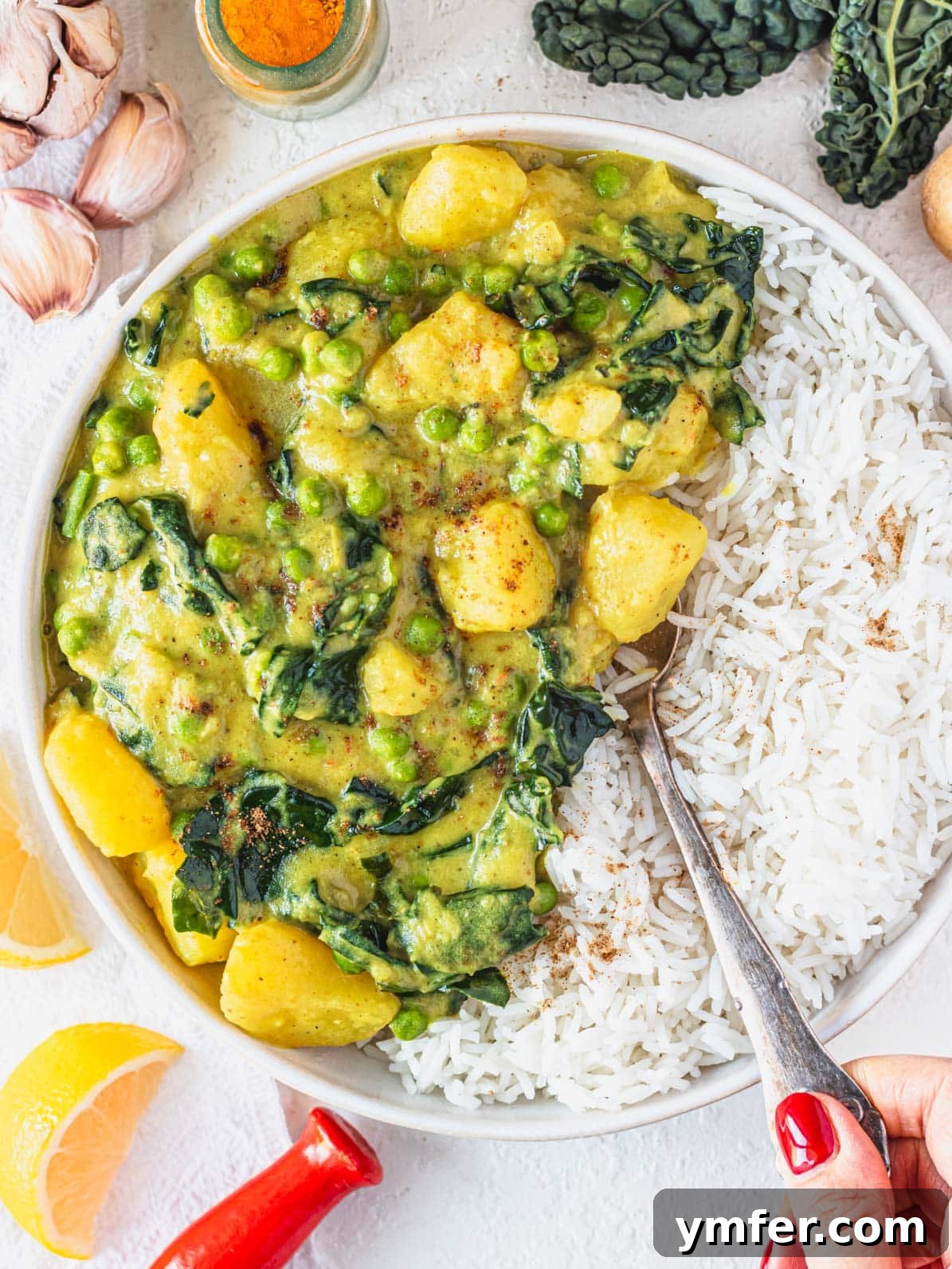 Golden Potato Delight 2 A vibrant bowl of creamy Potato Curry (Aloo Curry) served with fluffy rice, alongside a hand with red nail polish