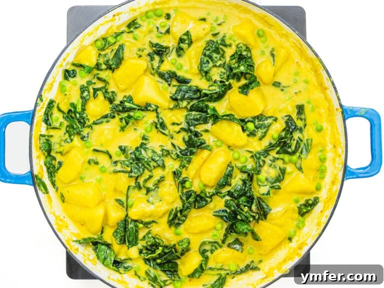 Kale, potatoes, and peas simmering harmoniously in the flavorful coconut sauce.