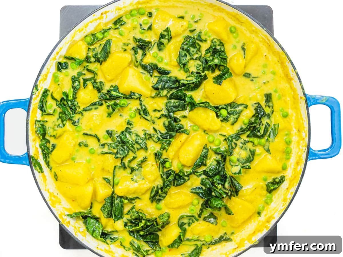 Golden Potato Delight 7 Wholesome kale, tender potatoes, rich coconut milk, and fragrant spices simmering together in a large skillet, nearing completion