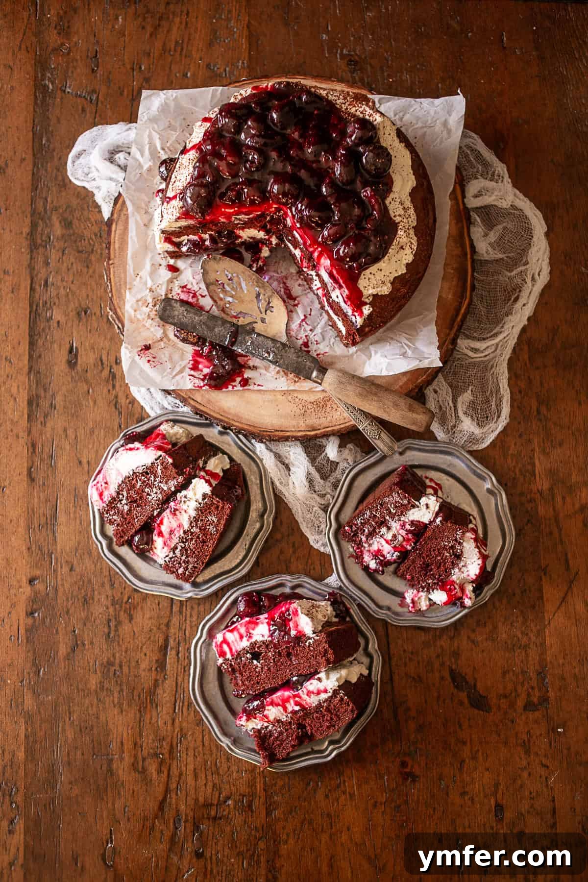 A Black Forest Cake on a platter, with three slices already served on small plates, showcasing its rich, layered interior.