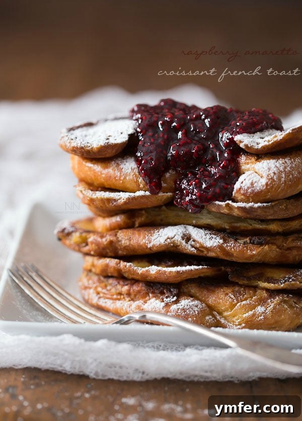 Decadent Amaretto Raspberry Croissant French Toast 2 stacked croissant french toast topped with raspberry sauce.