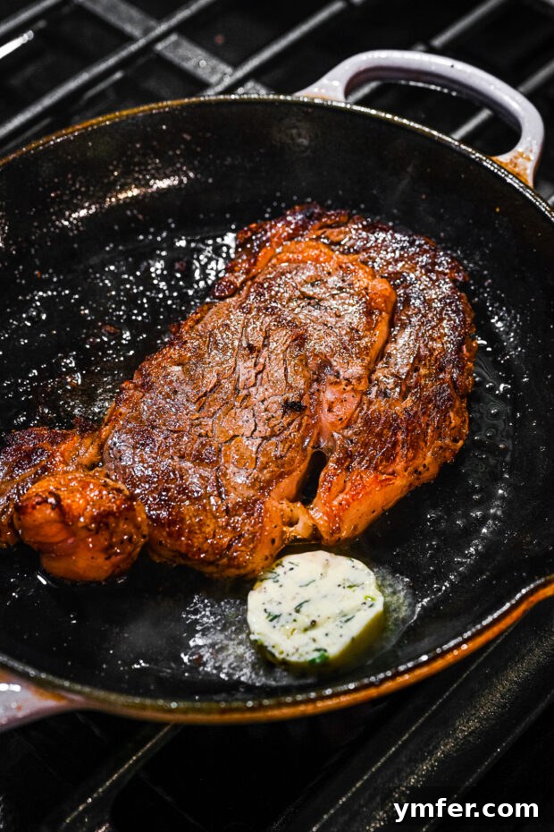 Perfect Pan-Seared Ribeye 6 A thick ribeye steak sizzling in a hot cast iron skillet, developing a dark, caramelized crust.