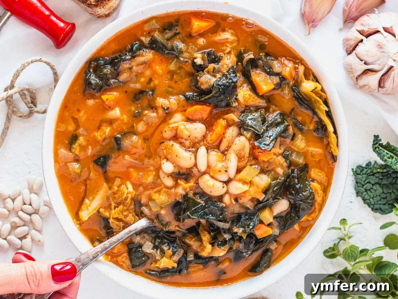 30 Plant-Based Protein Power Meals 12 Tuscan white bean soup with silver spoon and hand with red nail