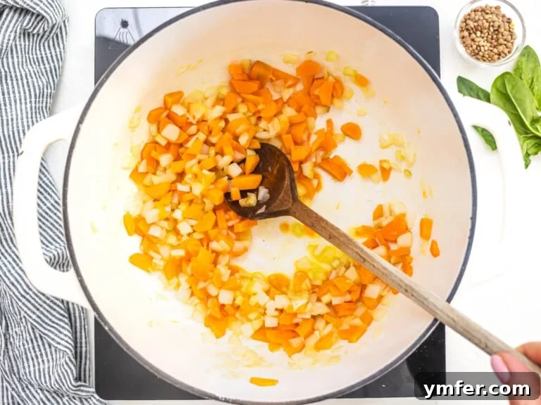 carrots and onion in a white pot frying