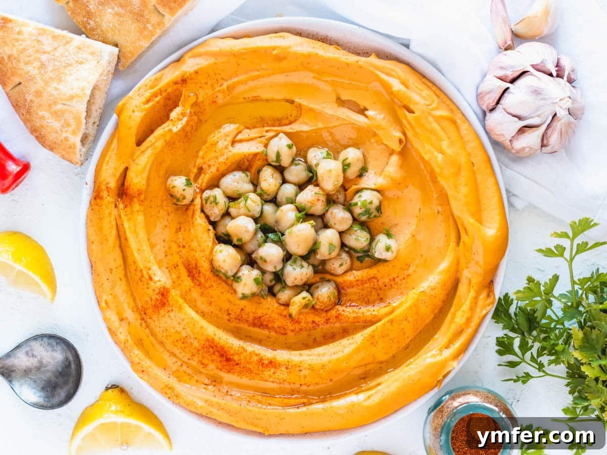 Velvety Roasted Red Pepper Hummus 3 Creamy roasted red pepper hummus garnished with fresh parsley and whole chickpeas.
