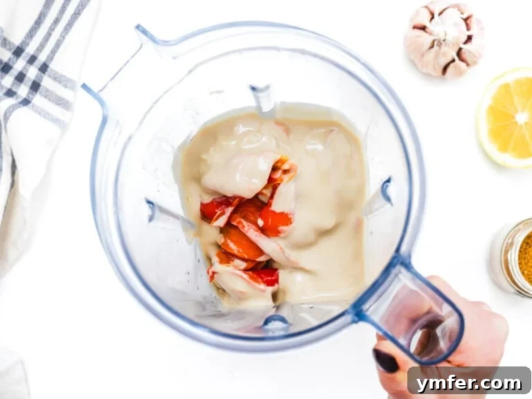 Velvety Roasted Red Pepper Hummus 18 tahini and red bell pepper in a blender held by a hand