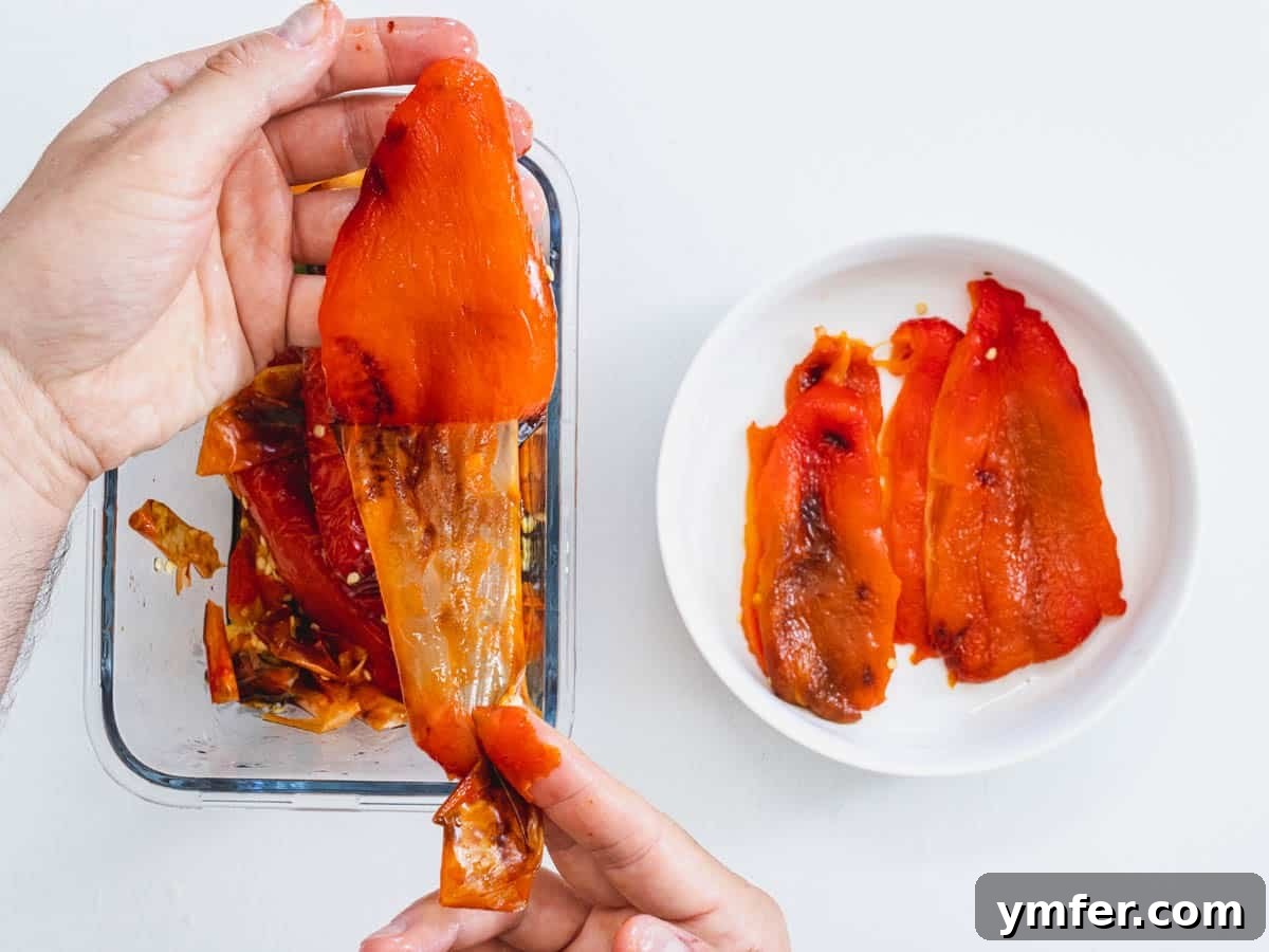 Velvety Roasted Red Pepper Hummus 8 A hand gently peeling the charred skin from a roasted red bell pepper.