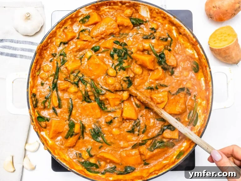 Soulful African Peanut Stew 16 creamy stew with sweet potato and spinach in a skillet with a wooden spoon