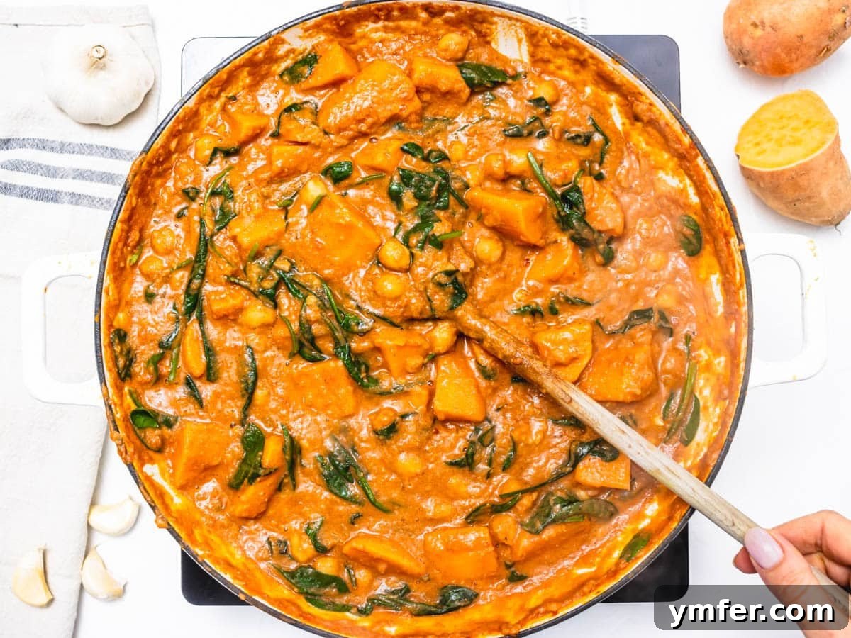 Soulful African Peanut Stew 10 creamy stew with sweet potato and spinach in a skillet with a wooden spoon