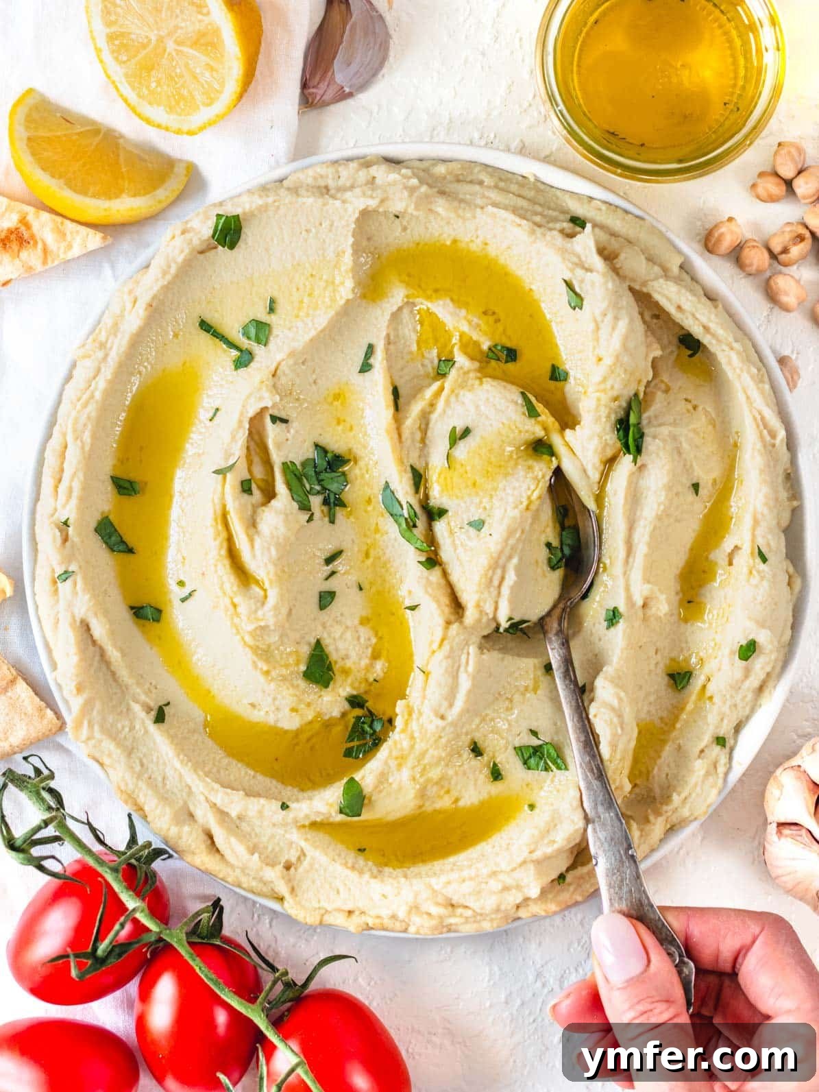 Hummus without tahini and a hand holding a silver spoon