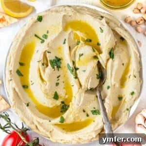 Hummus without tahini on a plate with a spoon and fresh parsley