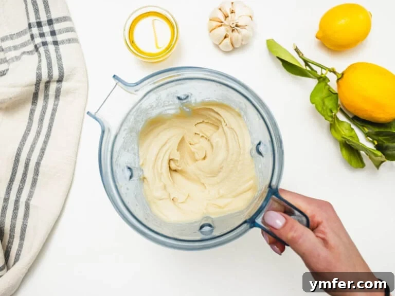 Hummus without tahini in a blender and a hand holding the handle