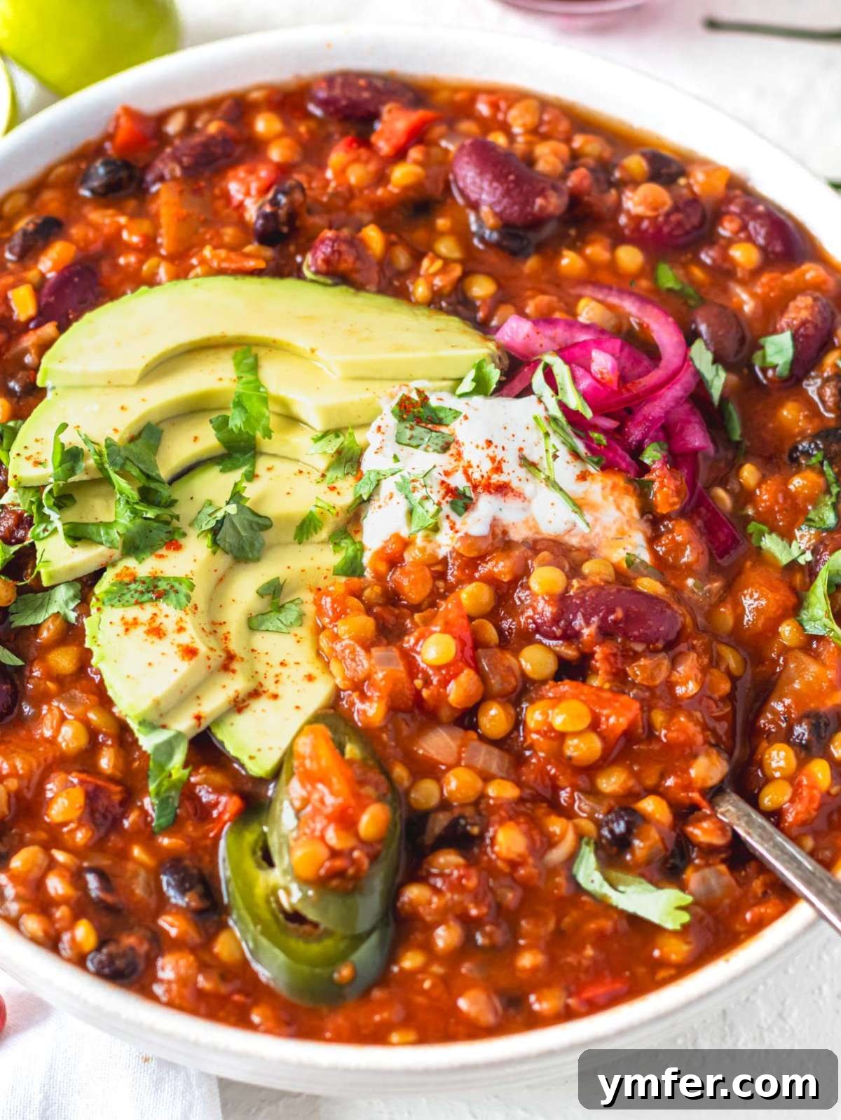 Hearty Lentil Chili 2 Hearty lentil chili garnished with creamy sour cream and vibrant jalapeños.